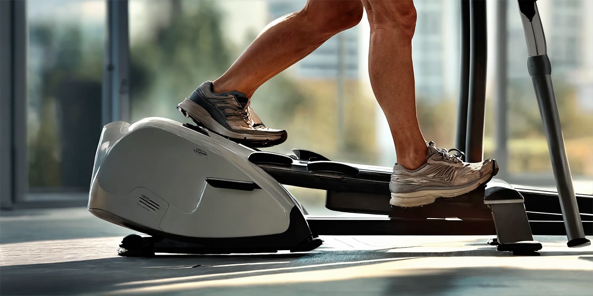 An individual engaging in a health-focused workout on a compact elliptical machine conveniently set up in their office space.