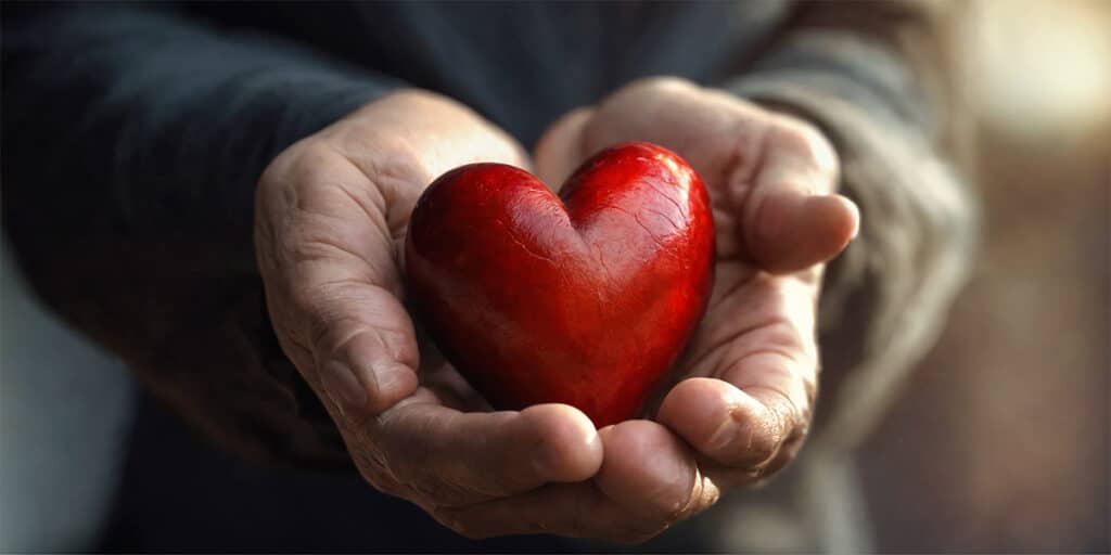 A person holding a vibrant, healthy heart in their hands, symbolizing care and wellness.