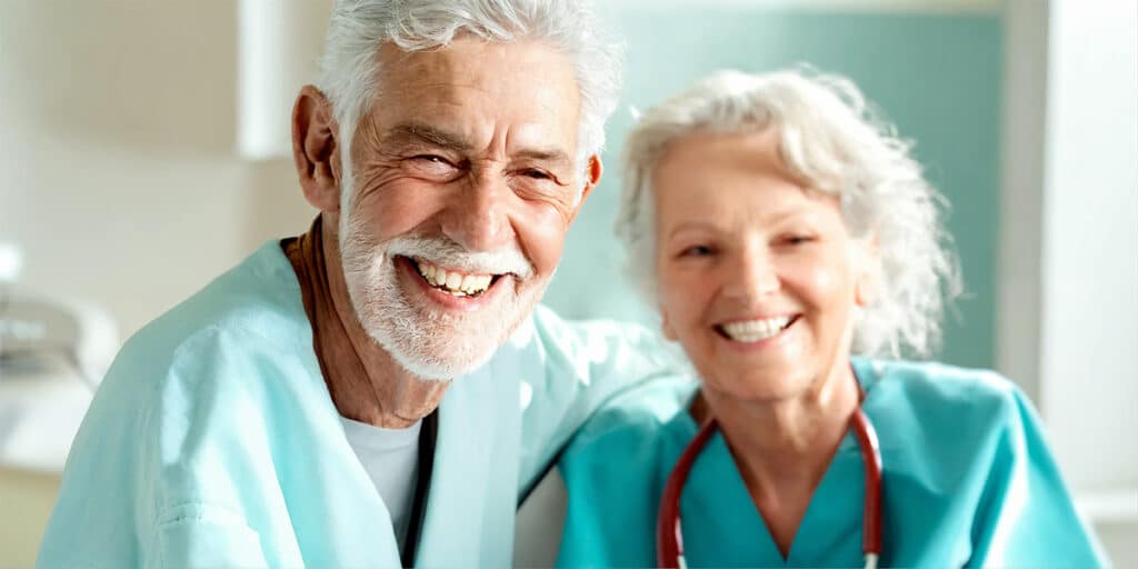 A senior citizen flashing a bright, healthy smile next to their dentist, showcasing the positive outcomes of dental care.