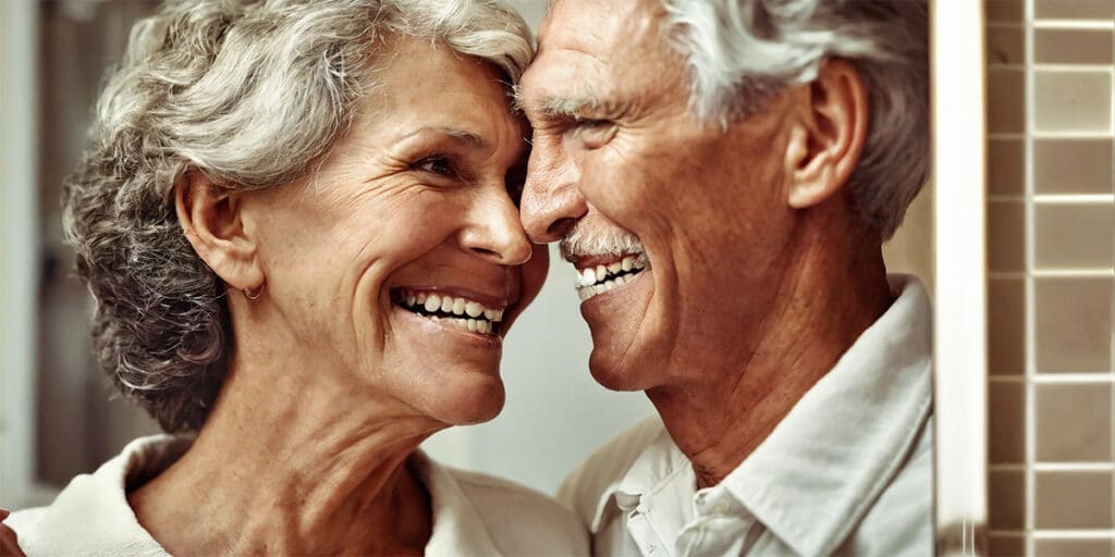 A senior couple engaging in their oral care routine, comparing their bright smiles reflecting a shared commitment to dental health.