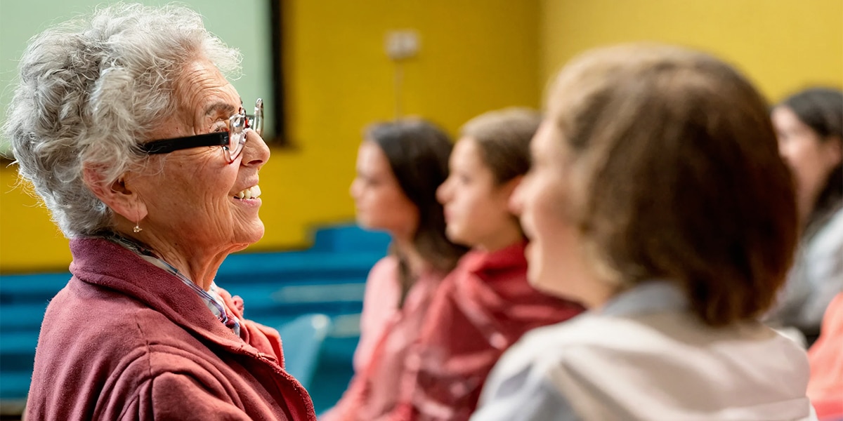 A senior attentively learning about oral health disease prevention from a younger female teacher symbolizing the exchange of knowledge across generations.